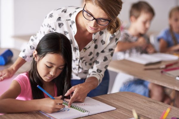 Teacher helping girl in homework